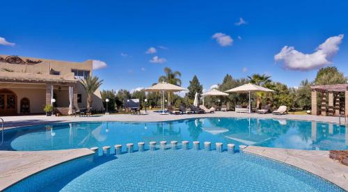a swimming pool at a resort with umbrellas at Palais Amador in Oulad Mazoug