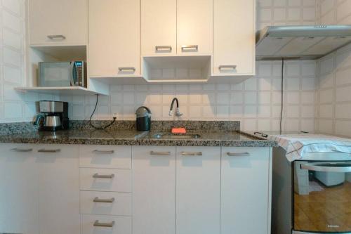 uma cozinha com armários brancos e um lavatório em Apartamento 3 Quartos Central com Ar SQ41 em Maringá