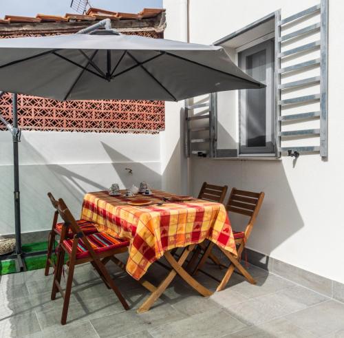 a table and chairs under an umbrella on a patio at NIKA NIKA Holiday House in Carini