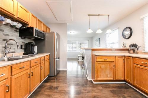 a kitchen with wooden cabinets and a stainless steel refrigerator at 4BR Gameday Getaway EV Charger Pet-Friendly 10p in South Bend