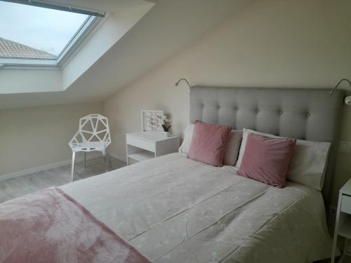 桑坦德的住宿－Apartamento de diseño. Moderno y acogedor. 2，一间卧室配有一张带粉红色枕头和椅子的大床