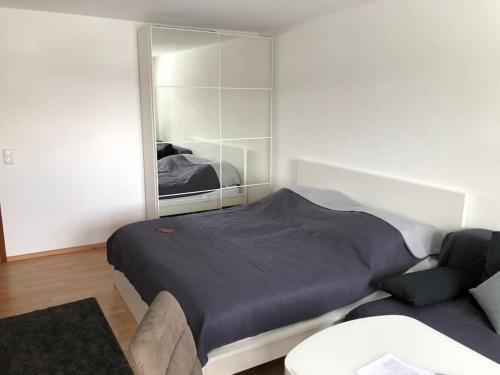 ein Schlafzimmer mit einem Bett, einem Spiegel und einem Sofa in der Unterkunft Schwarzwald Apartment mit Terasse in Schönwald