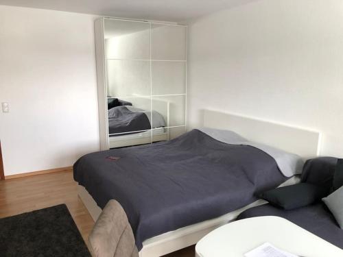 1 dormitorio con cama, espejo y sofá en Schwarzwald Apartment mit Terasse, en Schönwald