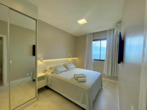 - une chambre avec un lit blanc et un grand miroir dans l'établissement Arpoador Vista Mar, à Rio de Janeiro