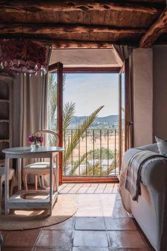 a bedroom with a bed and a table and a window at ES CUCONS RURAL HOTEL in San Antonio