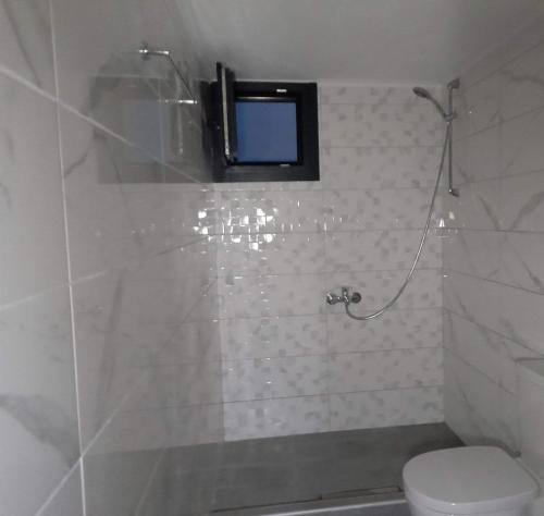 La salle de bains est pourvue de toilettes et d'une télévision murale. dans l'établissement Waterview Villa, à Chrysi Ammoudia