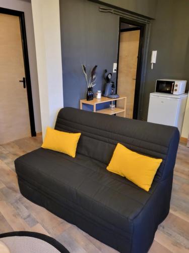 - un canapé noir avec des oreillers jaunes dans le salon dans l'établissement Appartement rénové, à Leffrinckoucke