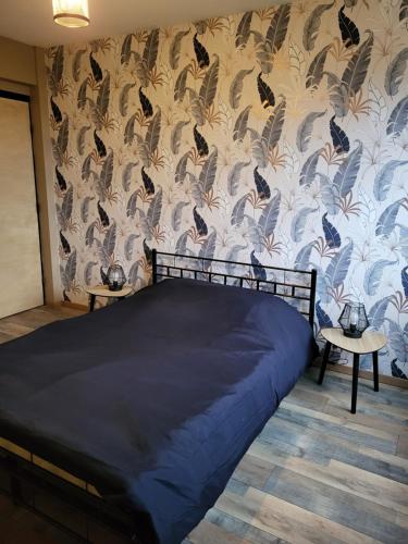 ein Schlafzimmer mit einem Bett und einer Tapete mit Schmetterlingen in der Unterkunft Appartement rénové in Leffrinckoucke