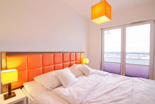 1 dormitorio con 1 cama con cabecero naranja y ventana en High Tower Szczecin en Szczecin