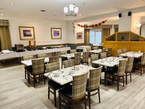 um restaurante com mesas e cadeiras num quarto em Loch Long Hotel em Arrochar