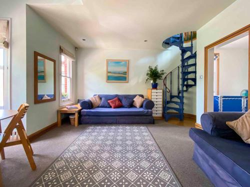 a living room with a blue couch and a spiral staircase at 8 Ravenscourt Gardens in London