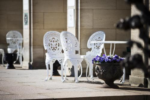 a group of white chairs and a table and a pot of flowers at Bofors Hotel in Karlskoga