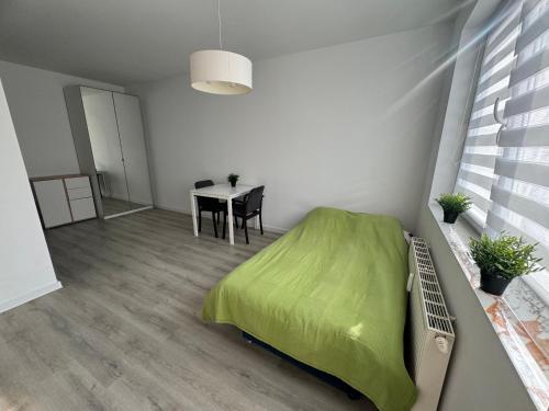 sypialnia z zielonym łóżkiem i stołem w obiekcie Apartament Katowicka w Poznaniu