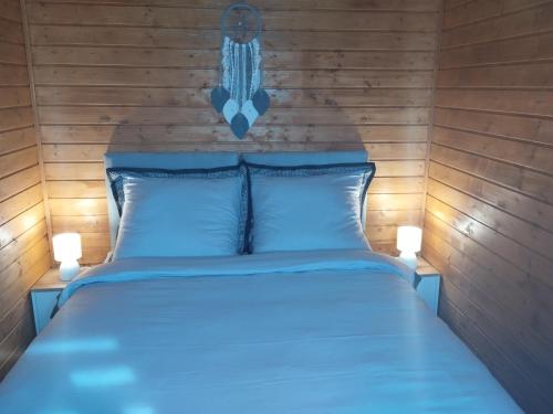 a bedroom with a blue bed with two lights on it at Winiec Mobile Home in Miłomłyn