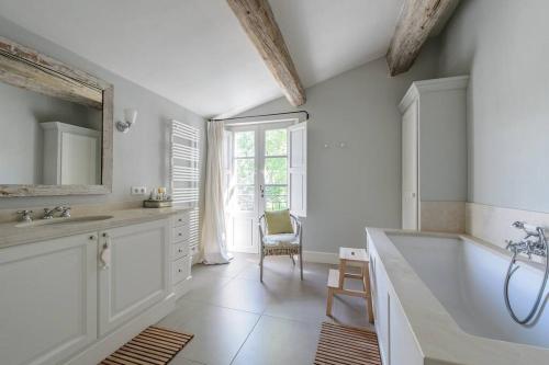 een badkamer met een bad, een wastafel en een spiegel bij Mas provençal avec piscine et tennis in Oppède