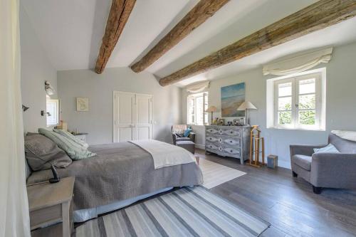 een slaapkamer met een bed, een stoel en een dressoir bij Mas provençal avec piscine et tennis in Oppède