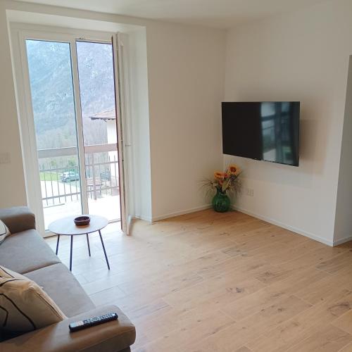 a living room with a couch and a tv on a wall at APPARTAMENTO LA FUCINA in Molina di Ledro