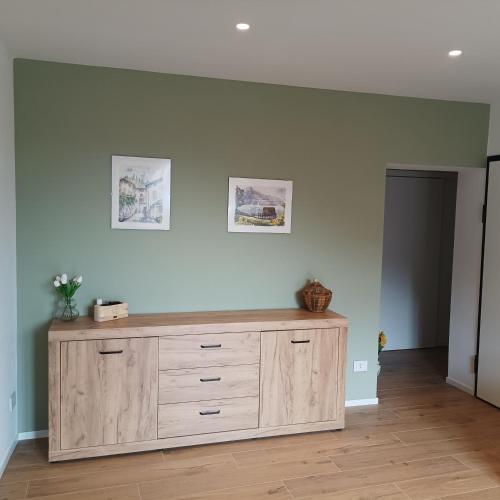 a wooden dresser in a room with two pictures on the wall at APPARTAMENTO LA FUCINA in Molina di Ledro