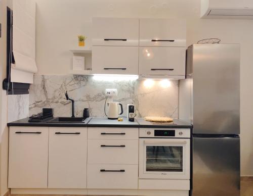 a kitchen with white cabinets and a stainless steel refrigerator at Volos Guesthouse Konstantina in Volos