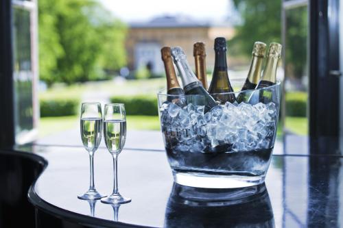 two glasses of wine sitting on a table with champagne bottles at Bofors Hotel in Karlskoga