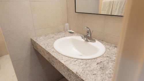 lavabo blanco en el baño con espejo en Clarkson Village Motel, en Mississauga