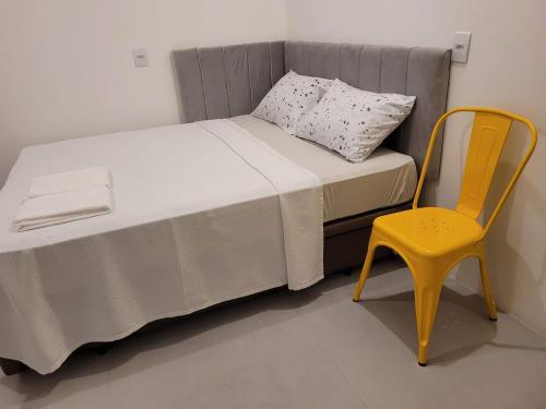 uma cama e uma cadeira amarela num quarto em Hostel & Suítes Stettin em Pomerode