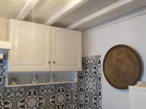 une cuisine avec des placards blancs et une horloge murale dans l'établissement Alex oldtown sea view rooms and appartments, à Mykonos