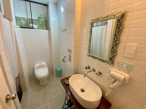 y baño con aseo, lavabo y espejo. en Serenity hotel & lodge en Ica