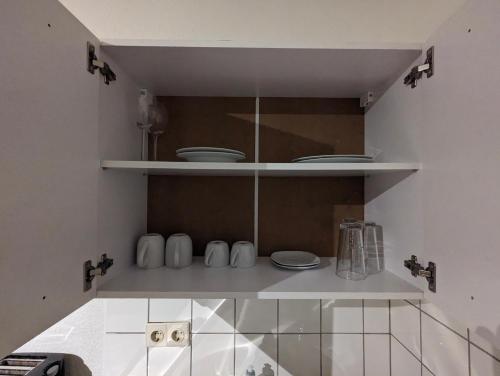 uma cozinha com copos e pratos brancos numa prateleira em City-Apartment & Lift ,Tannen C6 em Wuppertal