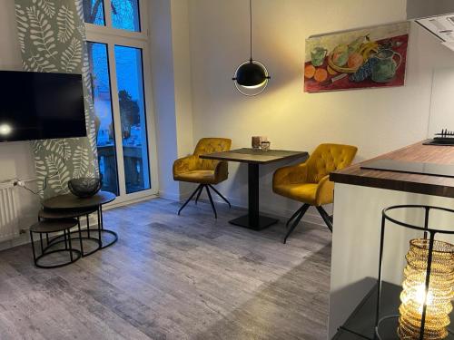 a living room with a table and yellow chairs at Laluna Modernes Wohnstudio mit Balkon im Herzen von Bad Rothenfelde in Bad Rothenfelde