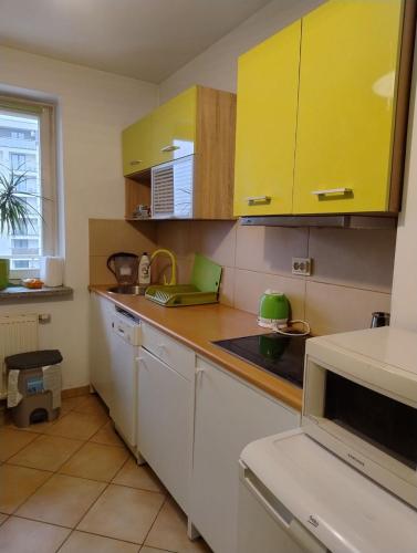 a kitchen with yellow cabinets and a laptop on the counter at GreenApartament in Krakow
