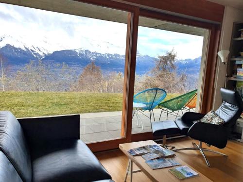 un soggiorno con una grande finestra con vista sulle montagne di Joli appartement 2 pièces et demi tout confort, Balcon du Ciel NAX Mont-Noble a Nax