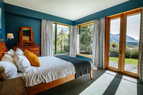 a bedroom with a bed and a large window at Bullock Creek Chalet - Sleeps 8 - Lake & Mountain Views - Private & Secluded in Wanaka