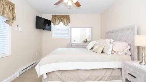 a white bedroom with a bed and a flat screen tv at Bay Ridge unit by Downtown Annapolis and Quiet Waters Park in Annapolis