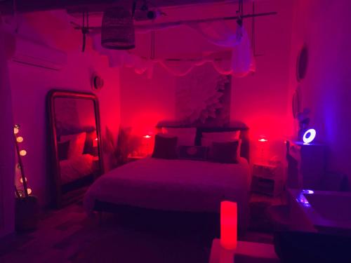 een slaapkamer met een bed met rode verlichting bij Love Appart Balnéo Jacuzzi Romantique Insolite in Le Barroux