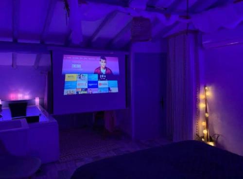 een woonkamer met een grote tv in een paarse kamer bij Love Appart Balnéo Jacuzzi Romantique Insolite in Le Barroux