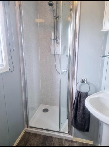 a shower with a glass door next to a sink at Sunrise Holidays Skegness - Ruby in Skegness