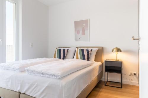 a bedroom with a white bed with a side table at living TIMELESS - Adler Apartments Sasbachwalden in Sasbachwalden