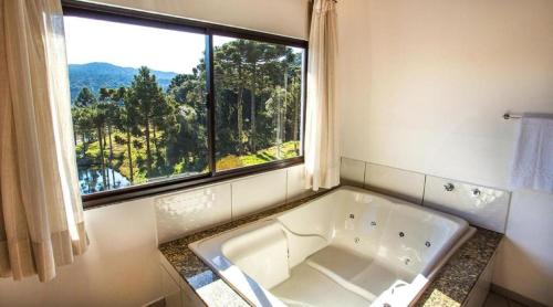 La salle de bains est pourvue d'une baignoire et d'une grande fenêtre. dans l'établissement Hibisco Home Hotel, à Urubici