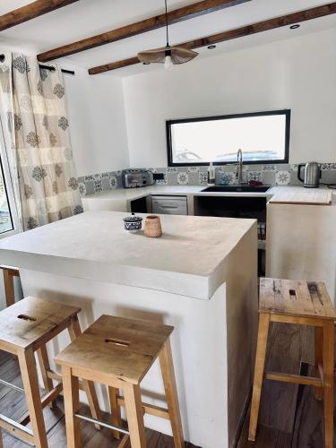 une cuisine avec un grand comptoir blanc et des tabourets en bois dans l'établissement Cabanon sur la plage vue sur les Sanguinaires, à Ajaccio
