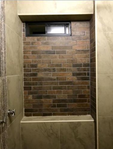 a bathroom with a brick wall and a window at Lovely 1 downtown studio in Rosarito