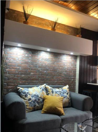 a blue couch with pillows in front of a brick wall at Lovely 1 downtown studio in Rosarito