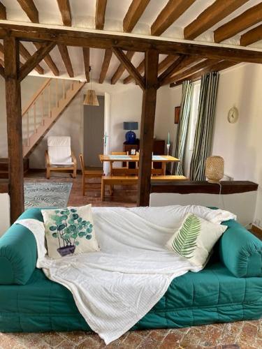 un salon avec un canapé vert avec des oreillers dans l'établissement Manoir de la Jaunière maison de charme Pays d’Auge, à Neuville-sur-Touques