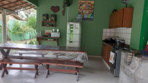 cocina con paredes verdes, mesa y barra en Refúgio Beira Mar, en Santa Cruz Cabrália