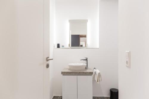a white bathroom with a sink and a mirror at living TIMELESS - Adler Apartments Sasbachwalden in Sasbachwalden