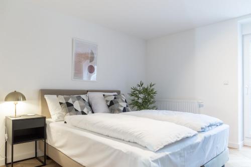 a white bedroom with a bed and a night stand at living TIMELESS - Adler Apartments Sasbachwalden in Sasbachwalden