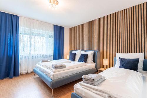 2 łóżka w pokoju z niebieskimi zasłonami w obiekcie lionApartments Leverkusen #2 w mieście Leverkusen