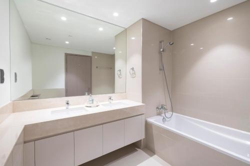 La salle de bains est pourvue de 2 lavabos, d'une baignoire et d'un miroir. dans l'établissement Luxury 2-BR Apt with Burj View, à Dubaï