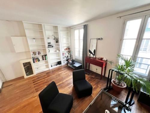 un soggiorno con pavimenti in legno e scaffali bianchi di Chaleureux appartement idéal JO a Courbevoie
