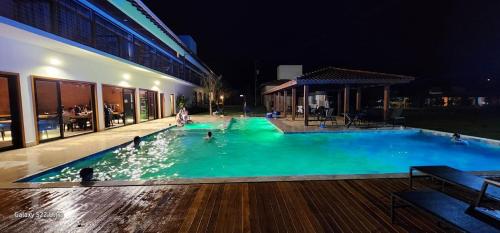 a swimming pool at night with people in the water at Paraíso Capitólio Suítes Pousada in Capitólio